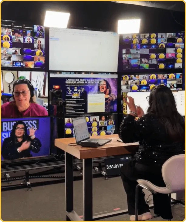 Alicia Lyttle broadcasting the AI Business Summit live from the studio with attendee video walls behind her